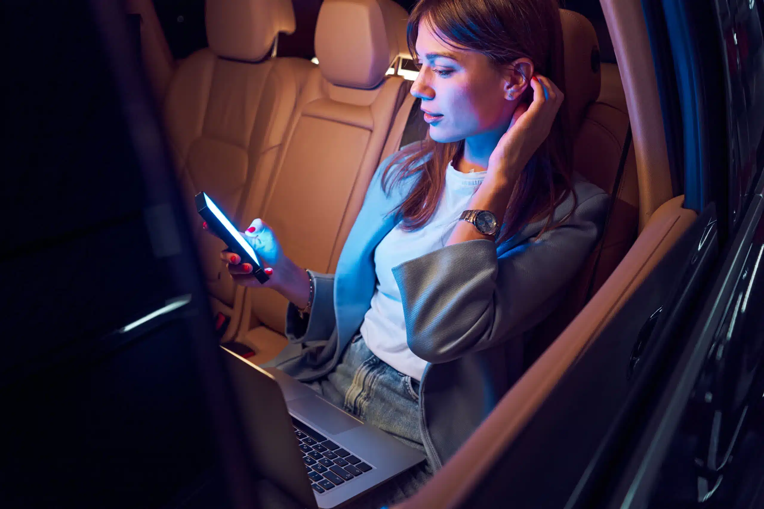 woman using smartphone and laptop in car jpg
