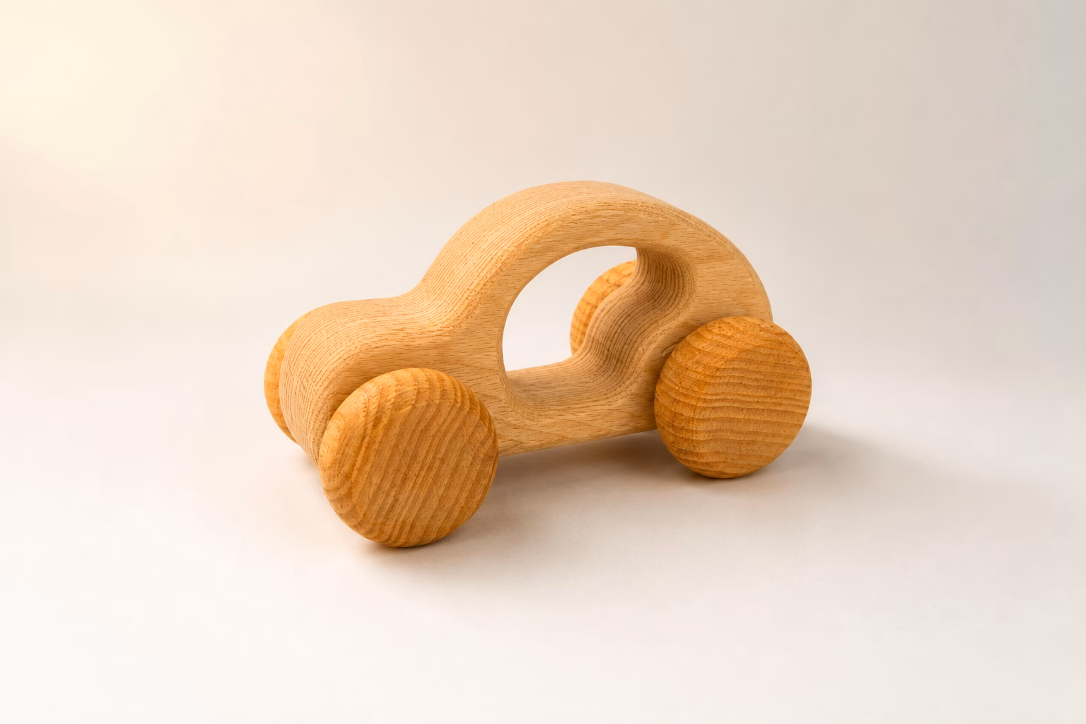 SaaS Agentur für B2B Produkte 12 Minimalistisches helles Holzspielzeug-Auto mit natürlicher Maserung, großem ovalem Griffausschnitt und vier einfachen Holzrädern in Dreiviertelansicht – weiches warmes Licht von links auf hellgrauem Studio-Boden